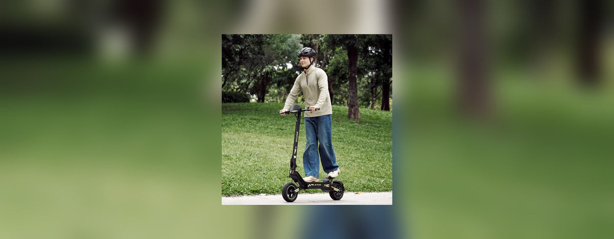 Man in a helmet riding a black isinwheel electric scooter along a park path