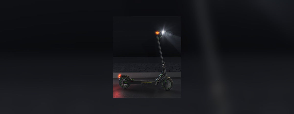 Black isinwheel electric scooter at night with its headlight and red rear light switched on