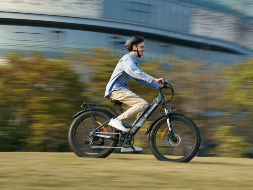 A rider on an isinwheel city e-bike, the background blurred by speed