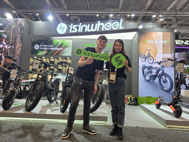 Zwei Mitglieder des isinwheel-Teams halten grüne isinwheel-Schilder vor dem Stand auf der IFA 2026