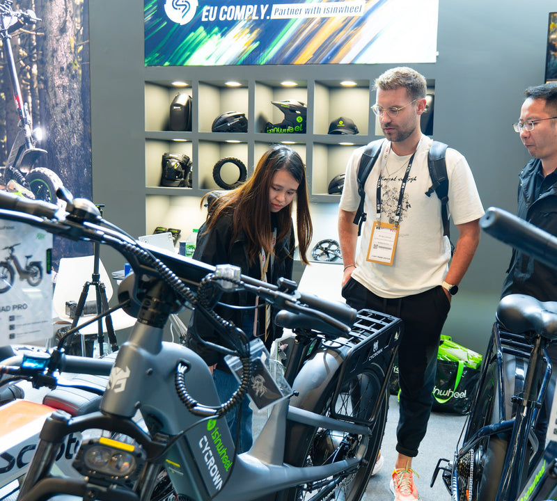 Zwei Besucher betrachten ein isinwheel Fatbike-E-Bike M60 am Stand